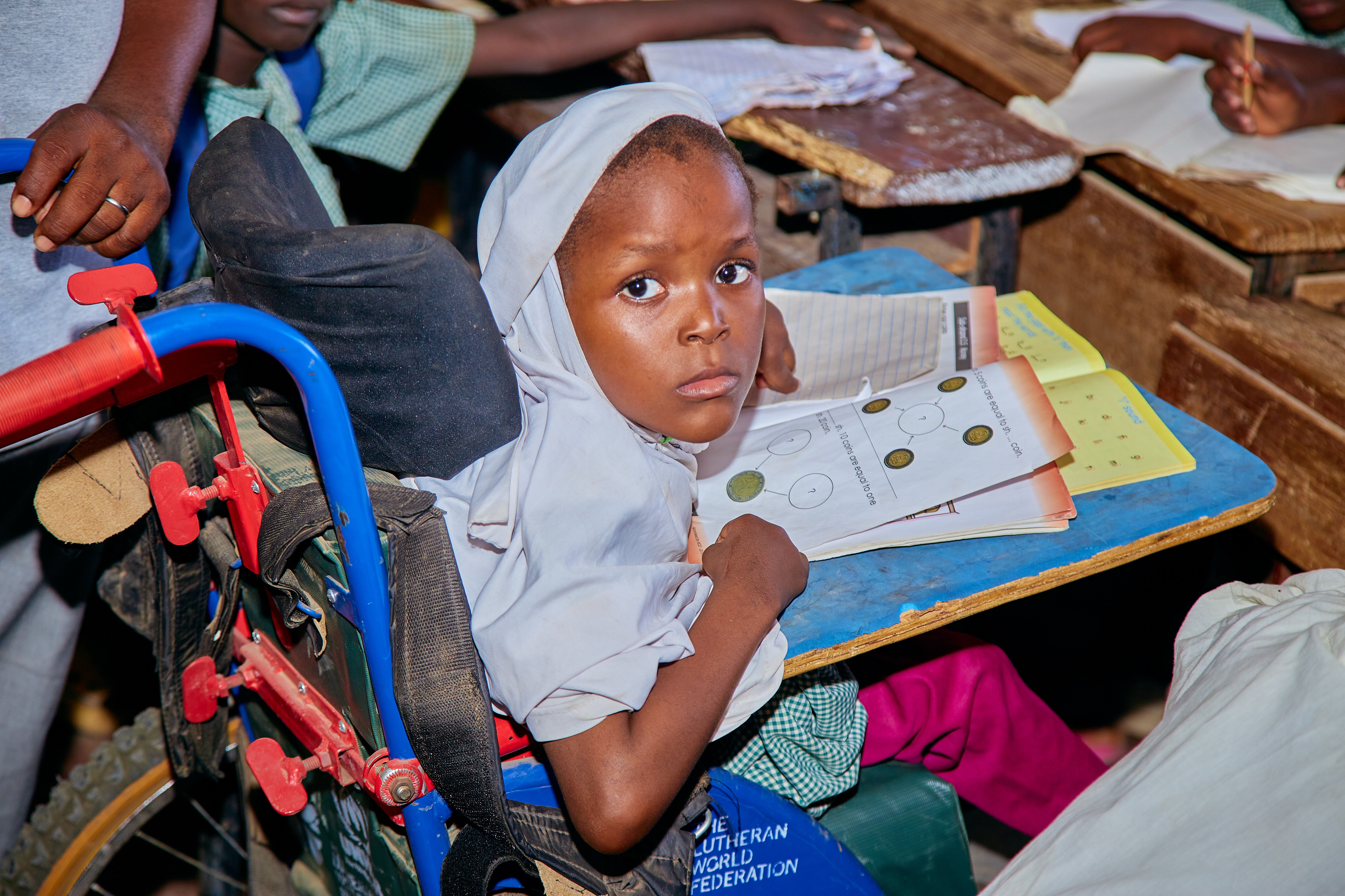 a little girl in a wheelchair does her homework at school 