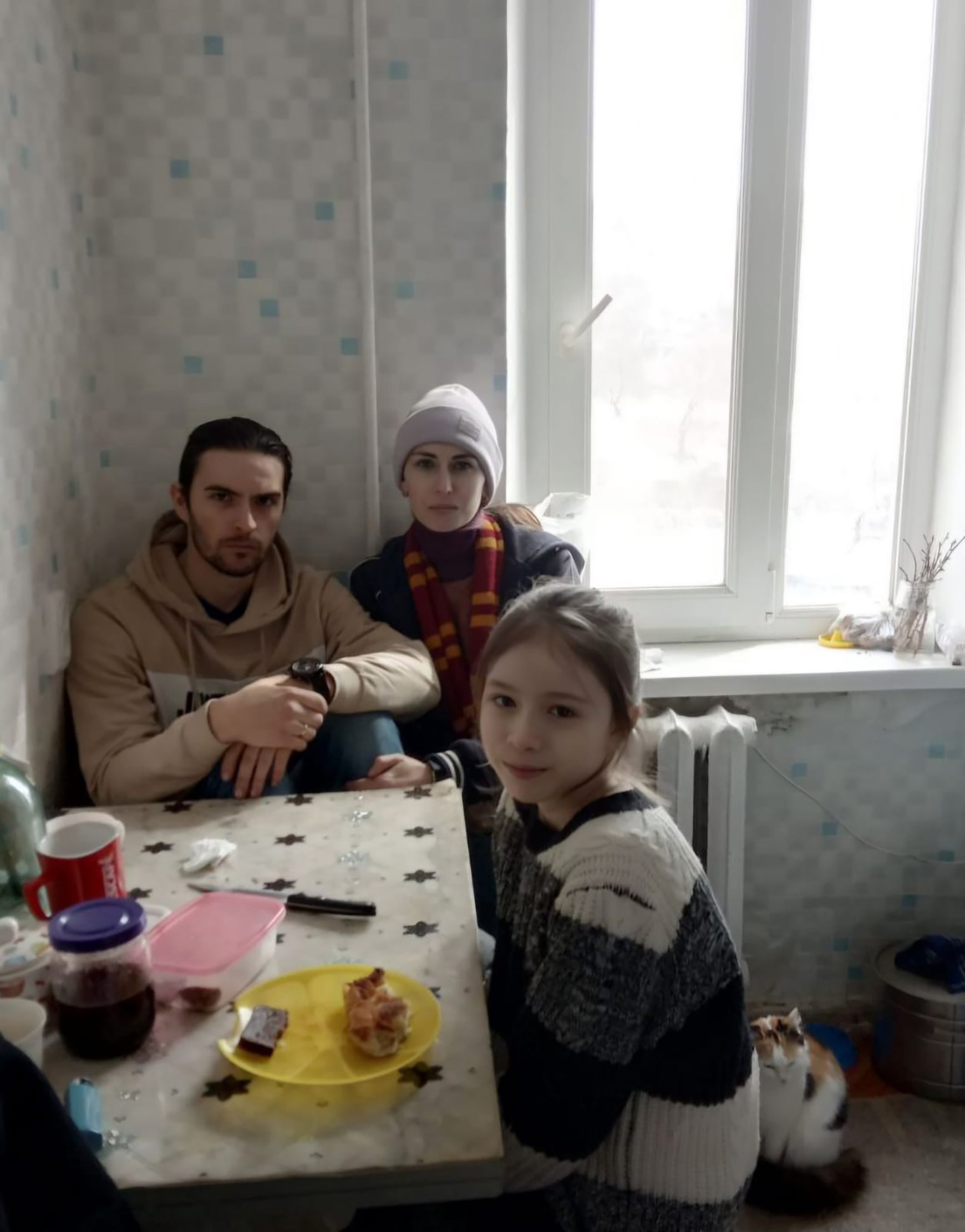 Antonina and her family posing in their kitchen, sitting at the table with winter clothes during the siege of their city