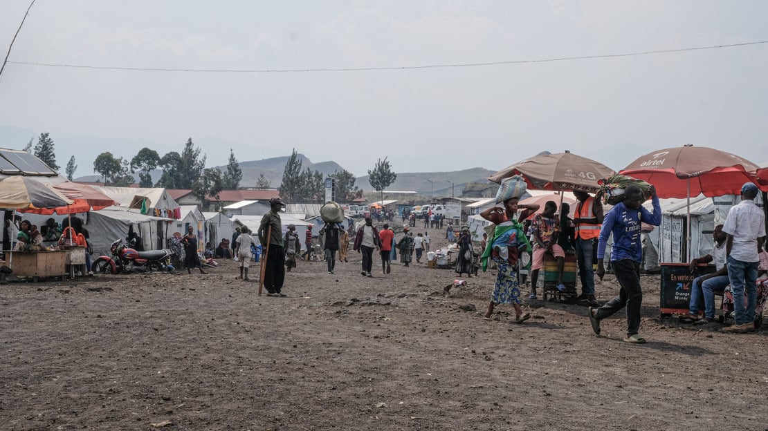 Overview of a street with passers-by and tents lining it.