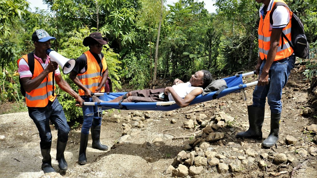 Des bénévoles portent une femme handicapée lors d’un exercice de simulation de catastrophe naturelle, à Haïti.; }}