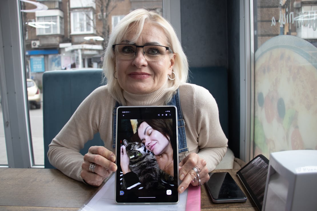 Elena, 53, and her daughter Yevgenia, 34, both survived bomb attack in eastern Ukraine. She is in a coffee shop showing a picture of her daughter and her cat. 